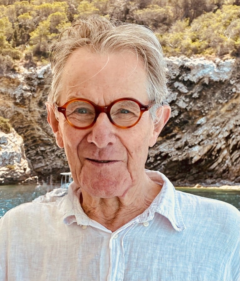 A man wearing round glasses and a white shirt